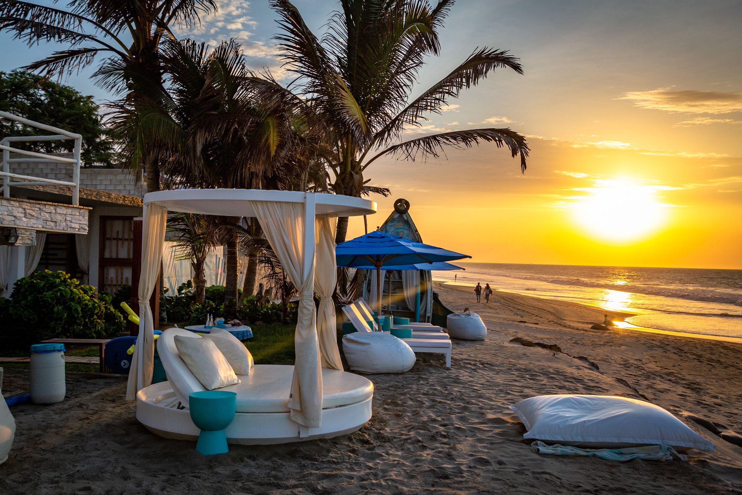 A beach setting with a sunlit sky, palm trees, and a beach umbrella.