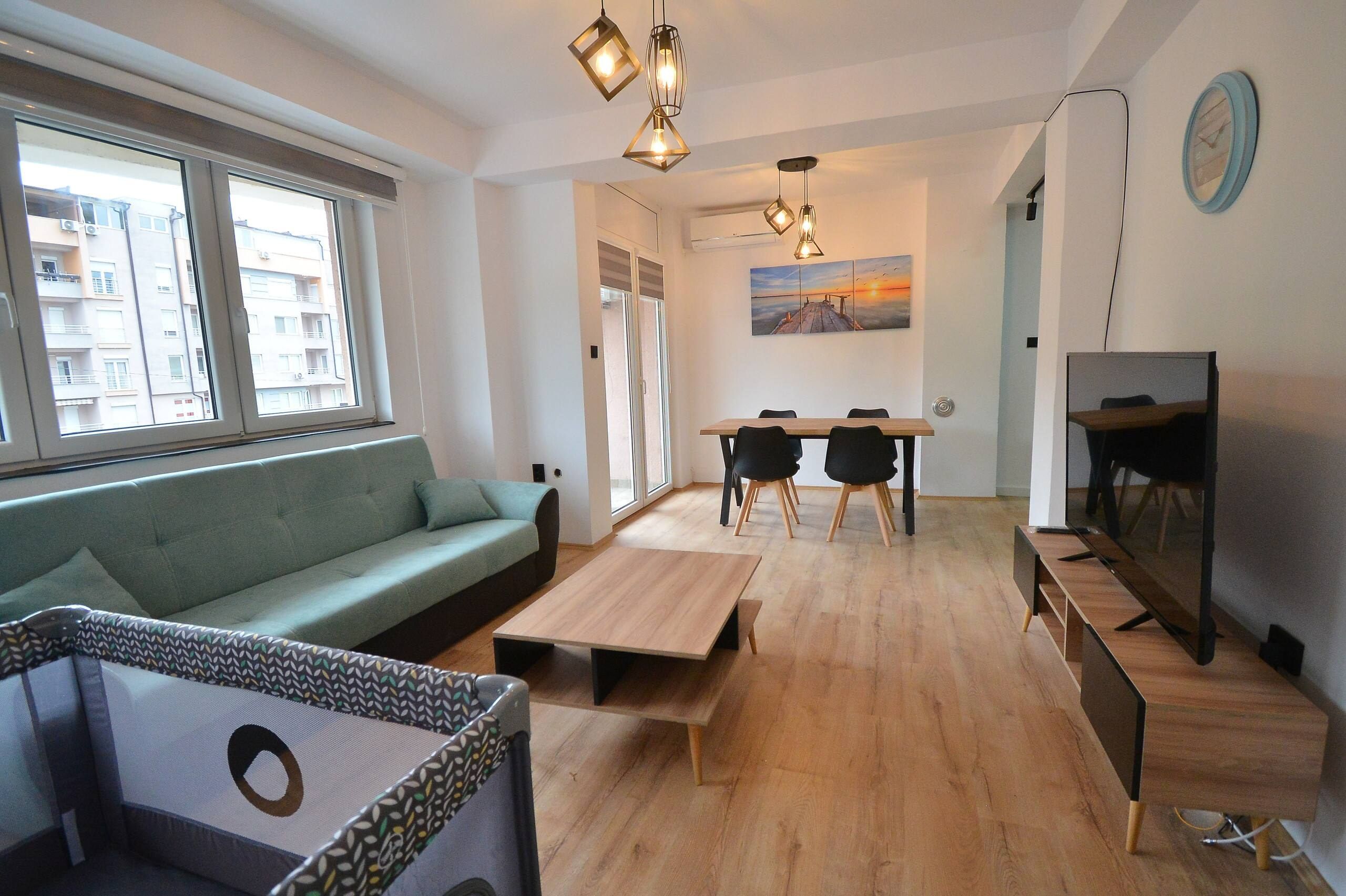 Un salon moderne avec un canapé, une table à manger et des chaises, un téléviseur et un tableau accroché au mur.