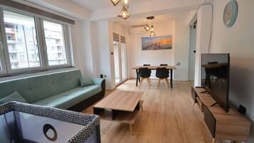 Un salon moderne avec un canapé, une table à manger et des chaises, un téléviseur et un tableau accroché au mur.
