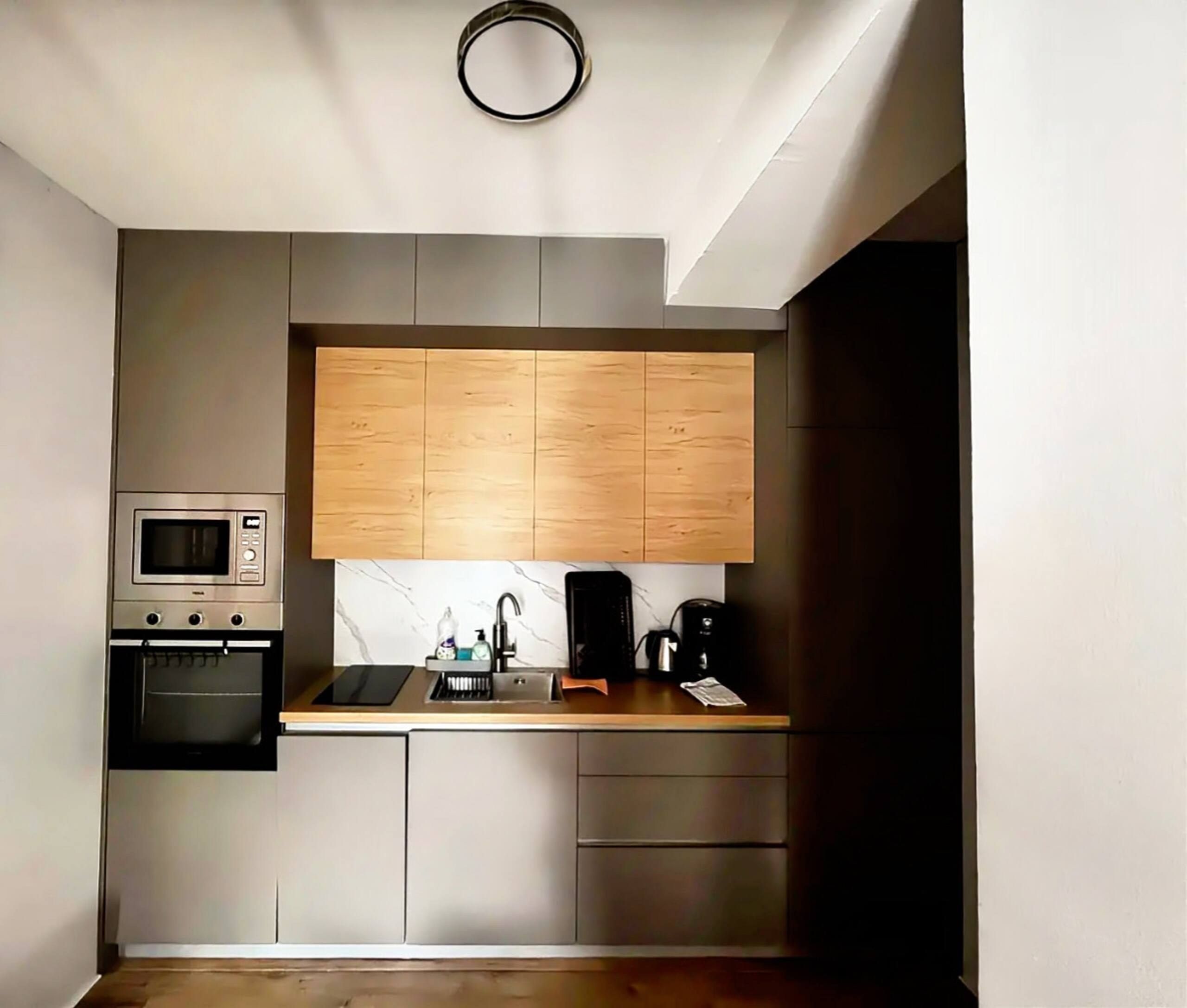 Cocina compacta con microondas, horno y cafetera integrados en la encimera.