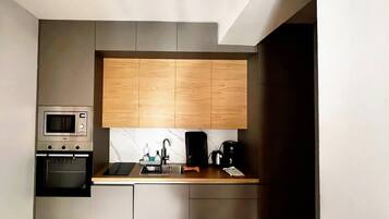Cocina compacta con microondas, horno y cafetera integrados en la encimera.