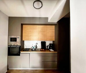 Cocina compacta con microondas, horno y cafetera integrados en la encimera.