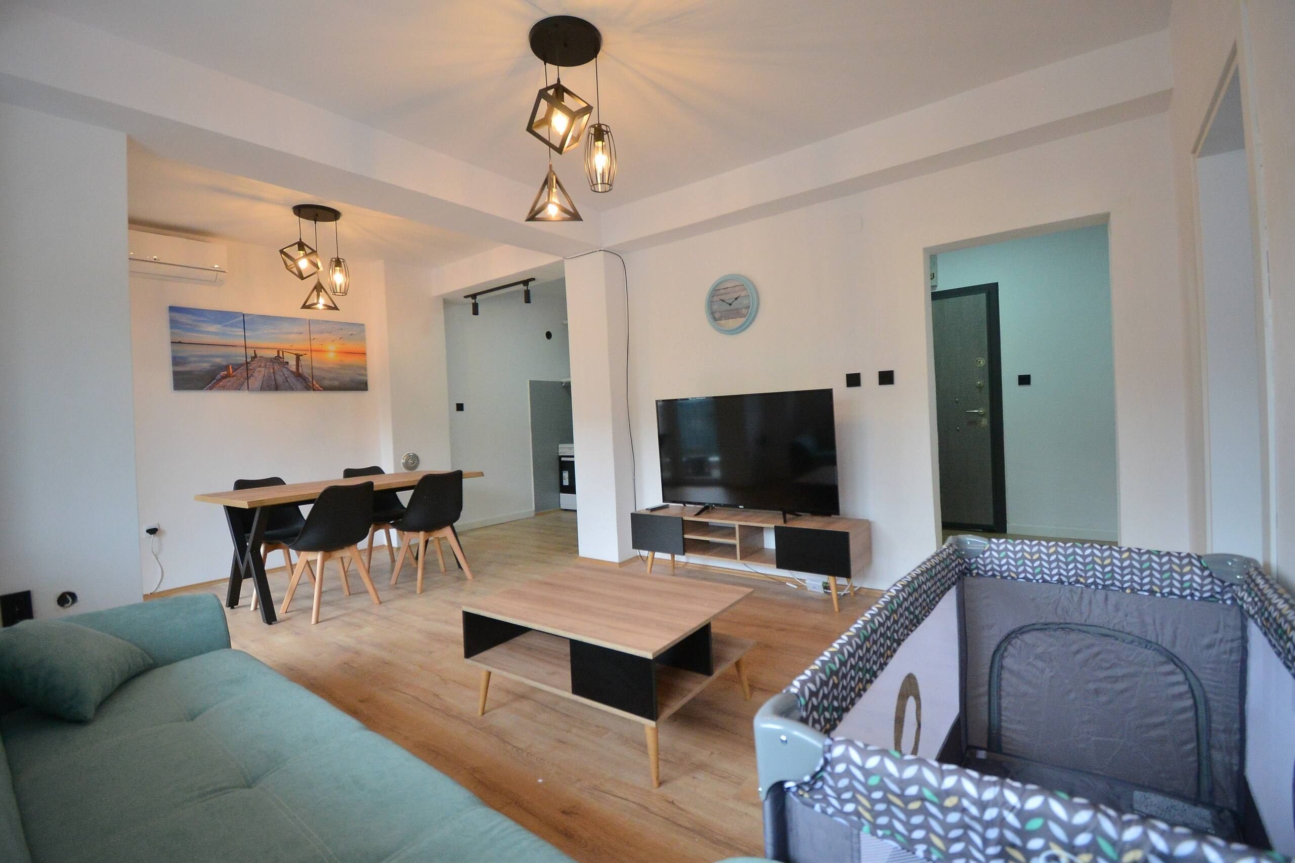 Een moderne woonkamer met een bank, een salontafel, een televisie en een eethoek met stoelen en een tafel.