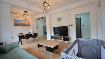 Een moderne woonkamer met een bank, een salontafel, een televisie en een eethoek met stoelen en een tafel.