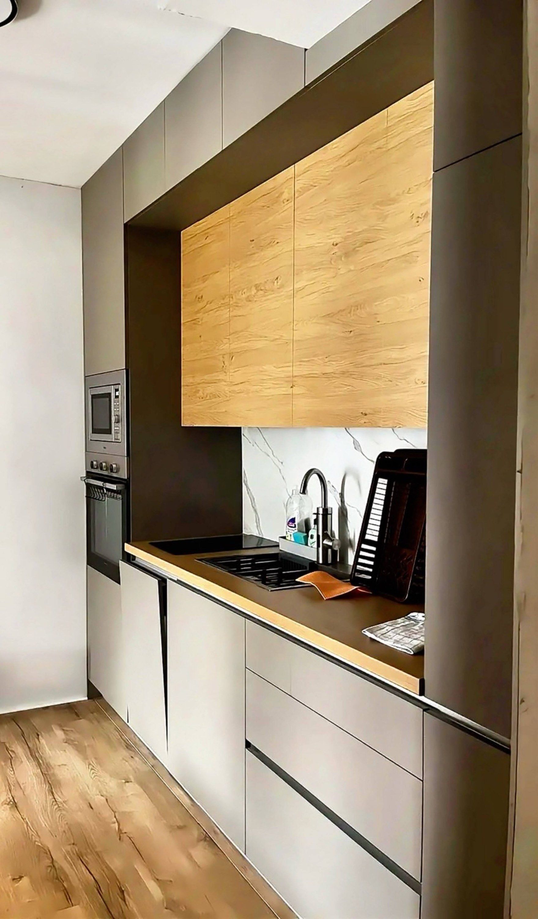 A modern kitchen with a built-in microwave, a sink with a faucet, and a stove.