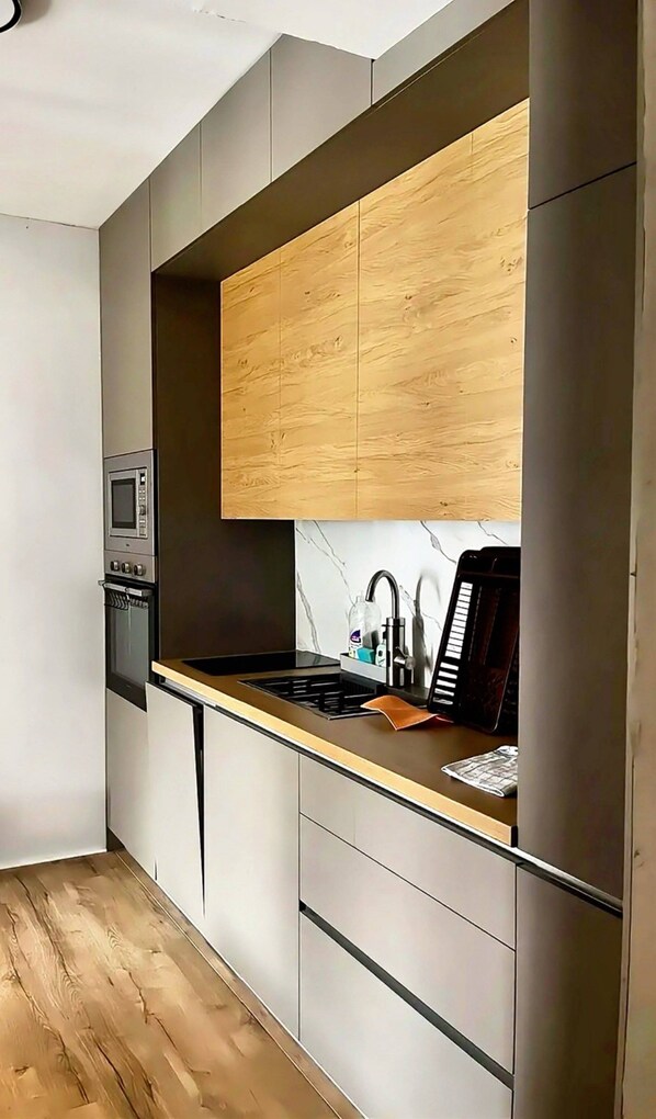 A modern kitchen with a built-in microwave, a sink with a faucet, and a stove.