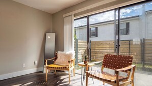 A modern living room with a large sliding glass door leading to a backyard, a wooden floor, and a large mirror. - Townhouse | USF - Moffitt - AdventHealth - Busch Gardens (Tampa)
