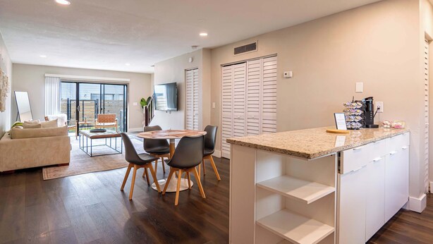 A modern apartment with a dining area, kitchen, and a balcony. - Townhouse | USF - Moffitt - AdventHealth - Busch Gardens (Tampa)
