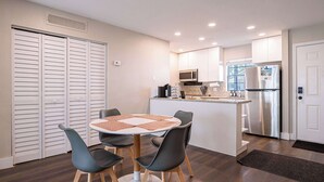 A compact kitchen with a central island, a dining area with four chairs, and a refrigerator. - Townhouse | USF - Moffitt - AdventHealth - Busch Gardens (Tampa)