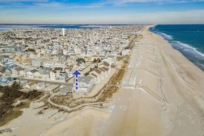 An aerial view of a coastal residential area with houses, a beach, and a lighthouse. - Lovely 3 bedroom townhouse, 1 house from the beach (Seaside Heights)