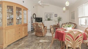 Un coin repas avec des chaises en osier, une nappe rouge et un buffet en bois doté de portes en verre.