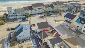 Un quartier résidentiel situé sur la côte, composé de plusieurs maisons à deux étages, d’une plage de sable et offrant une vue dégagée sur l’océan.