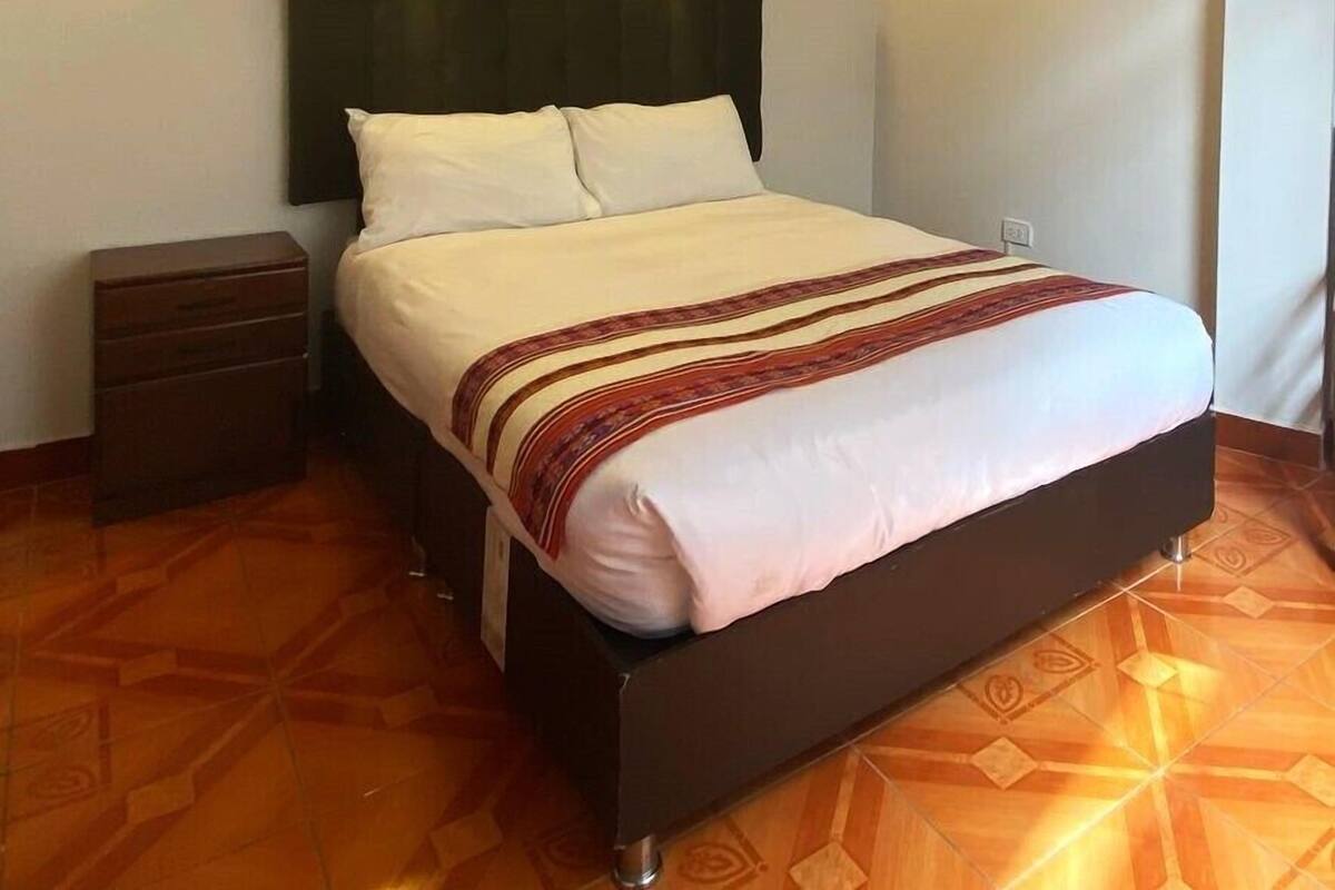 A bed with a dark headboard, two bedside tables, and a patterned bedspread.