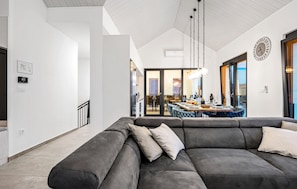 Relax in a spacious living area with a large sofa, contemporary light fixture, and expansive window views.