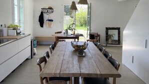 Ein geräumiger Essbereich mit Holztisch und -stühlen, einer Pendelleuchte und Blick ins Freie durch ein großes Fenster.