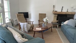 Ein Wohnzimmer mit einer Couch, Sesseln, einem Couchtisch und einem Kamin.