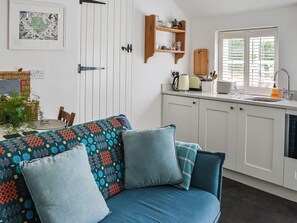 A modern kitchen with white cabinets, a sink, and a window with blinds. - 1 bedroom accommodation in Benllech (Benllech)