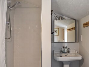 A bathroom with a shower, a sink, and a mirror. - 1 bedroom accommodation in Benllech (Benllech)