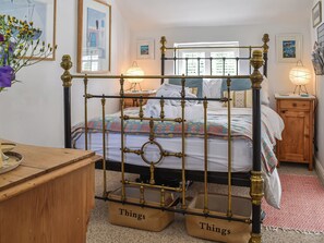 A bedroom with a four-poster bed, a wooden nightstand, a bedside table, and a wall-mounted lamp. - 1 bedroom accommodation in Benllech (Benllech)