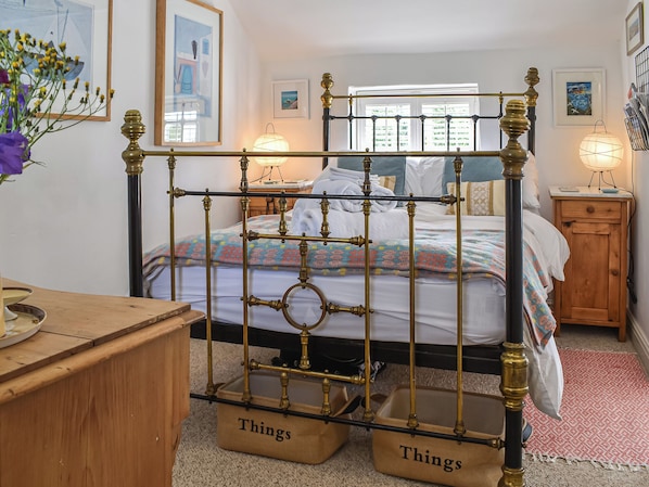 A bedroom with a four-poster bed, a wooden nightstand, a bedside table, and a wall-mounted lamp.