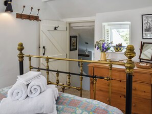 A bedroom with a bed, a dresser, a mirror, a window with a view, and a door leading to another room. - 1 bedroom accommodation in Benllech (Benllech)