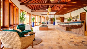 A spacious lobby with a high ceiling, wooden beams, and a large boat display. - MKNI Hotel - Makani Experience (Acaraú)