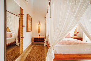 Una habitación con cama, mesita de noche, espejo y una lámpara fijada a la pared.