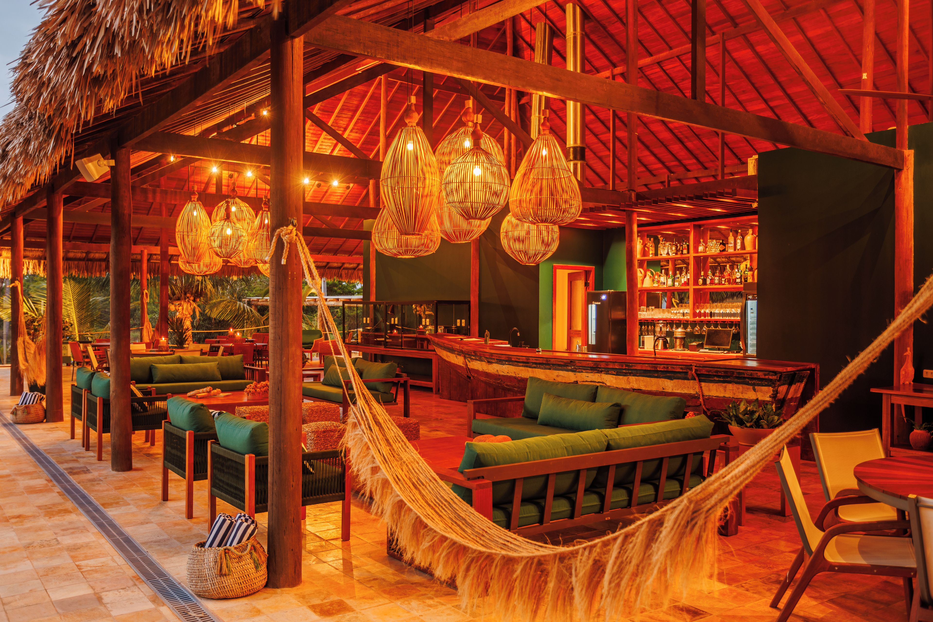 Zona de bar con temática tropical, que incluye mobiliario de mimbre, lámparas colgantes y una hamaca.
