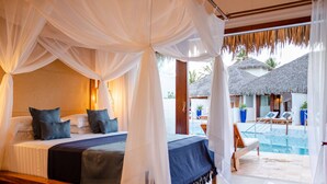 A bedroom with a canopy bed, a view of a pool, and thatched-roof structures in the background. - MKNI Hotel - Makani Experience (Acaraú)