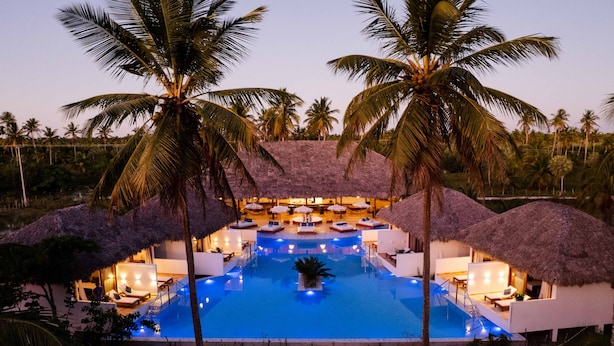 A resort with a central swimming pool, thatched-roof structures, and palm trees. - MKNI Hotel - Makani Experience (Acaraú)