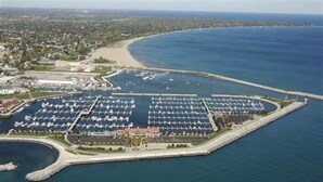 An aerial view of a marina with multiple docks and boats, surrounded by a coastal landscape. - Reef Point Marina - Vessel: "Freckled Fin" - East Dock 1, Slip 19 (Racine)