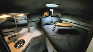 A compact, well-lit interior with bunk beds, a small kitchenette, and a single overhead light. - Reef Point Marina - Vessel: "Freckled Fin" - East Dock 1, Slip 19 (Racine)