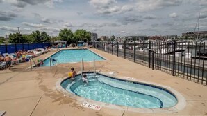 A swimming pool area with two pools, a fenced deck, and a marina in the background. - Reef Point Marina - Vessel: "Freckled Fin" - East Dock 1, Slip 19 (Racine)