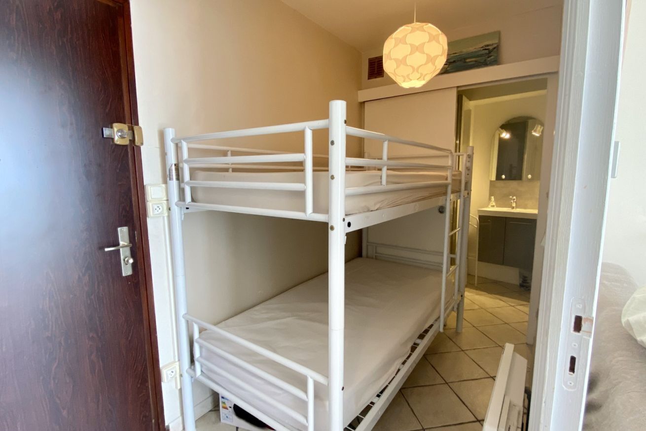A bunk bed in a room with a door, a light fixture, and a glimpse of a bathroom.