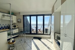 Eine moderne Küche mit Meerblick, ein Essbereich mit Stühlen und eine große Schiebeglastür.