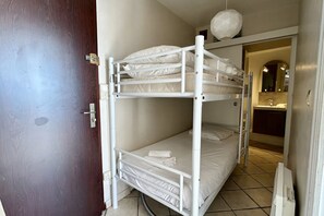 A bunk bed room with a door, a mirror, and a sink in the background.