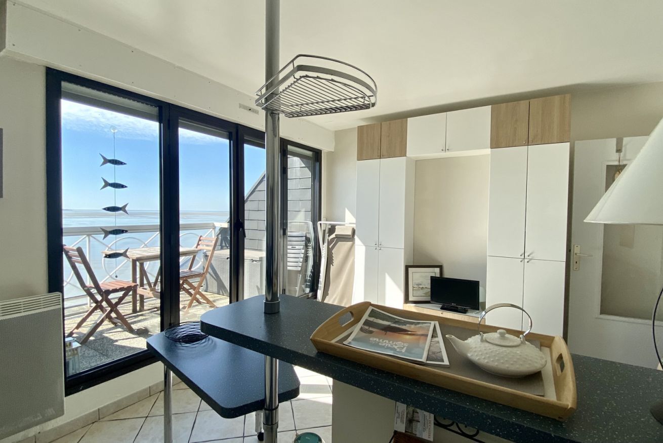 Una cucina moderna con vista sul mare, una zona pranzo con sedie e un piccolo tavolo con un vassoio.