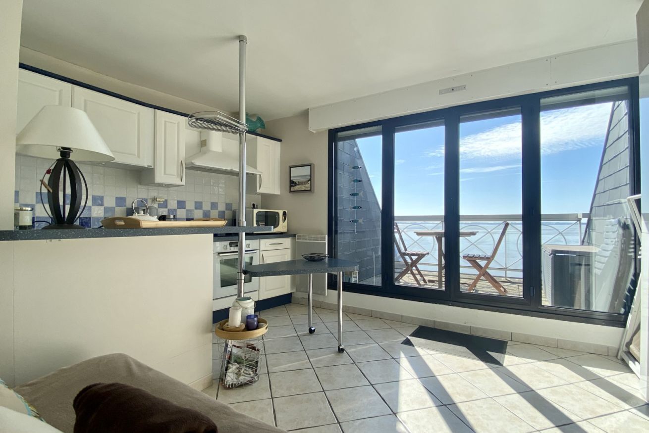 Une cuisine compacte avec vue sur la mer, un coin repas avec une table et des chaises, et une grande fenêtre.