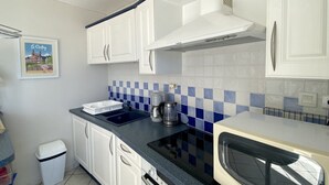 A kitchen with white cabinets, a blue and white tiled backsplash, a coffee maker, and a microwave.