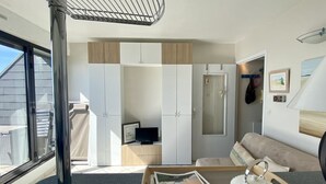 A modern interior with a sofa, a table with a magazine, a TV, and a wardrobe.