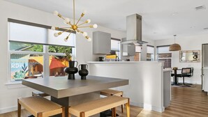 Una cucina moderna con isola centrale, panche in legno e un lampadario particolare.