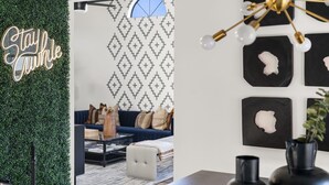 Un soggiorno moderno con una parete a motivi geometrici, un divano blu e un tavolino da caffè.