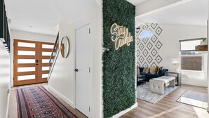 Un soggiorno moderno con una parete verde, una scala e un tappeto decorato.
