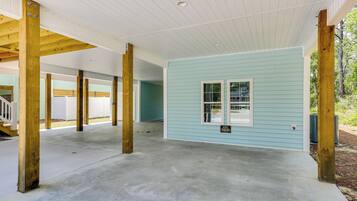 A spacious covered area with concrete flooring, wooden beams, and a light blue exterior wall.