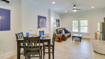 A spacious living area with a dining table, chairs, a sofa, and a ceiling fan.