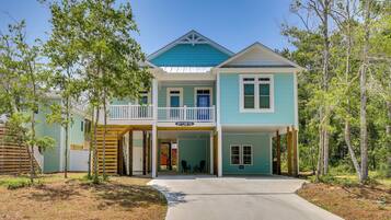 A two-story house with a balcony, a covered front porch, and a driveway leading to the entrance.