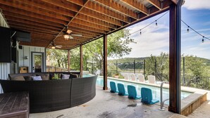 Un espace extérieur abrité comprenant une piscine, des sièges et une vue sur les collines.