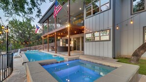 Une maison moderne dotée d’une piscine, d’un espace salon extérieur et de guirlandes lumineuses.