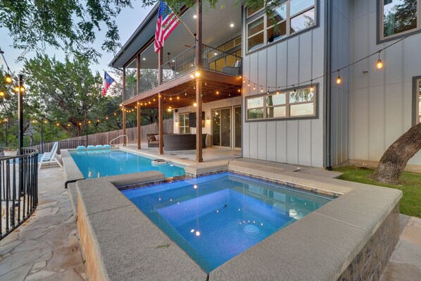 Une maison moderne dotée d’une piscine, d’un espace salon extérieur et de guirlandes lumineuses.