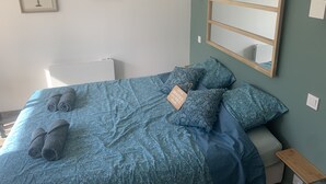 A bedroom with a bed, pillows, a bedside table, a mirror, and two framed pictures on the wall. - Gite "bambou" Avec Piscine (Beauvallon)